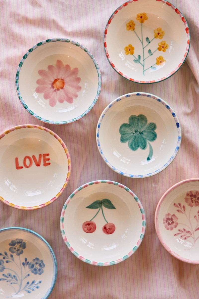 Verschiedene handbemalte Keramikschüsseln mit Blumen, Kleeblatt, Kirschen und dem Wort LOVE