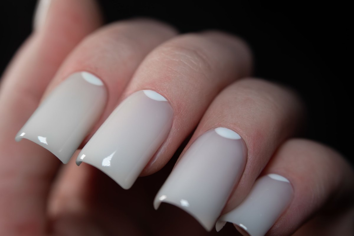 Eckige Acrylnägel in milchigem Weiß mit kleinem Halbmond-Detail am Nagelbett