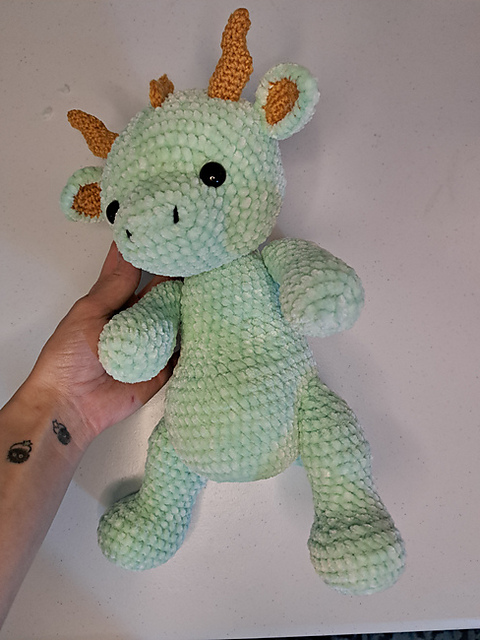 Mintgrüner flauschiger Häkeldrache aus dickem Chenillegarn mit orangefarbenen Hörnern