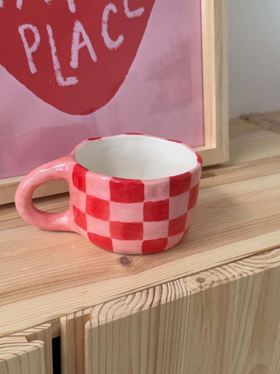 Handbemalte Keramiktasse mit einem Schachbrettmuster in Rosa und Rot