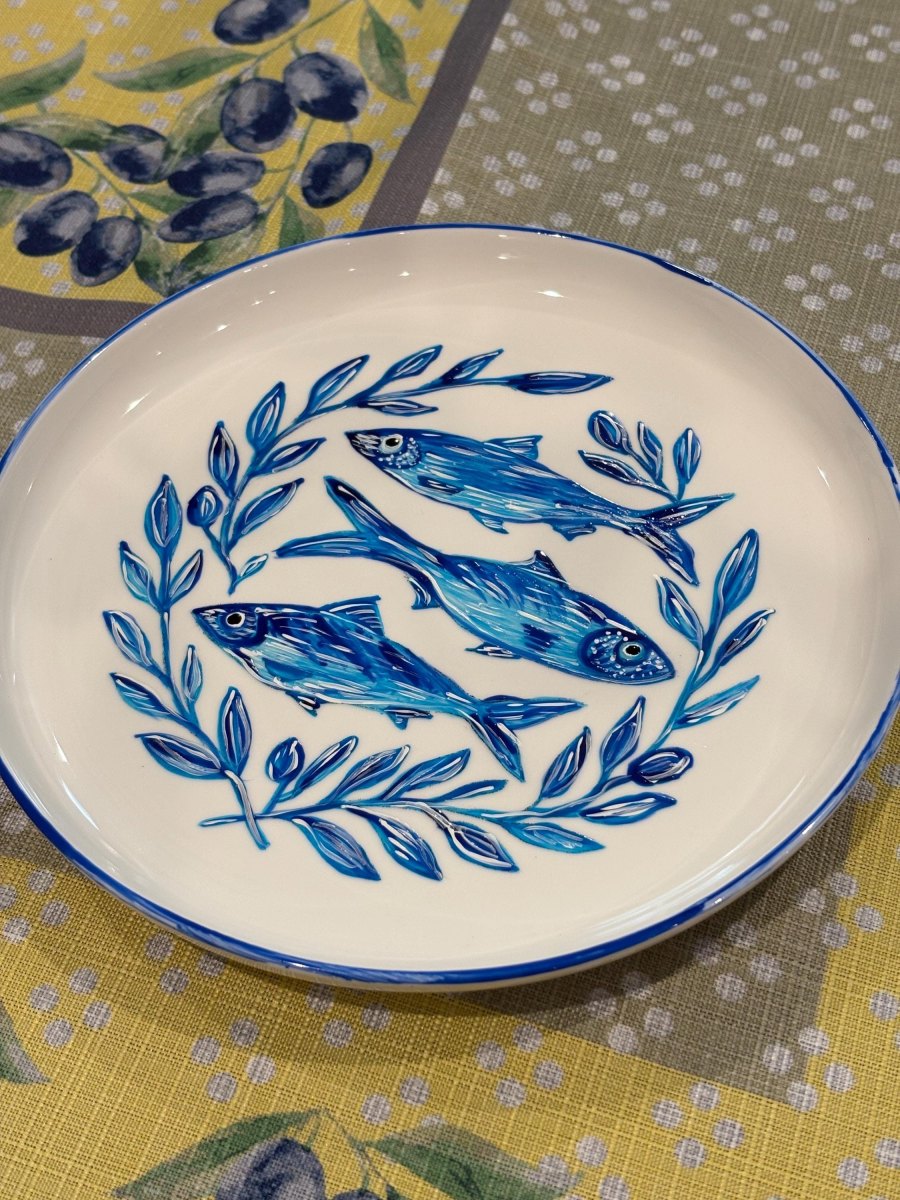 Weißer Keramikteller bemalt mit blauen Sardinen und Blättern