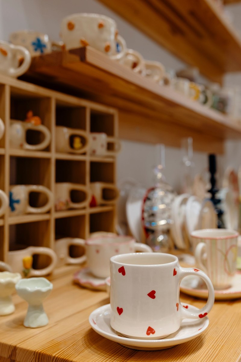 Weiße Keramiktasse mit Untertasse bemalt mit kleinen roten Herzen