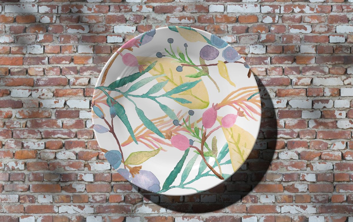 Keramikteller mit zarten botanischen Blättern und Zweigen in Pastellfarben im Aquarell-Stil