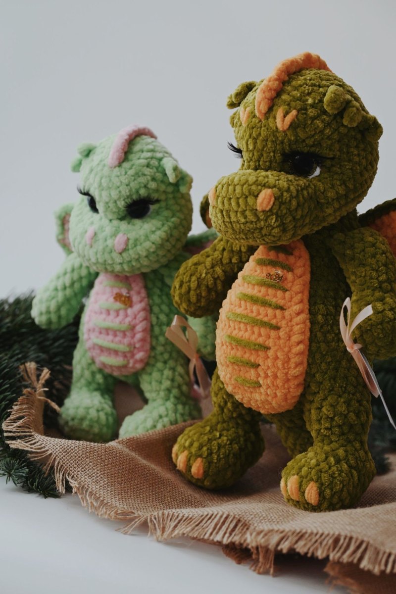 Zwei flauschige Amigurumi-Drachen aus Samtgarn in Mint-Rosa und Olivgrün-Orange