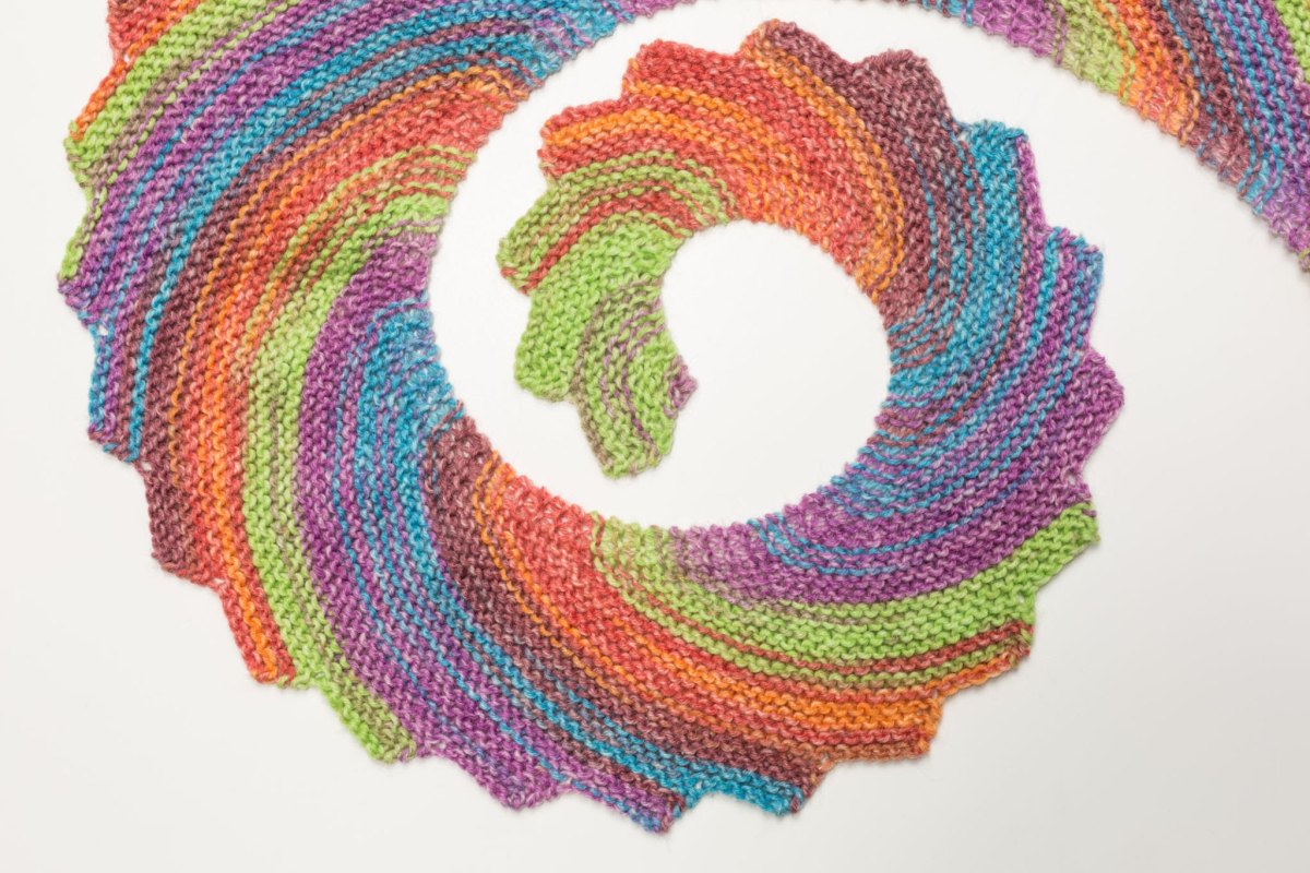 Spiralig gelegter bunter Drachenschwanz-Schal in leuchtenden Regenbogenfarben