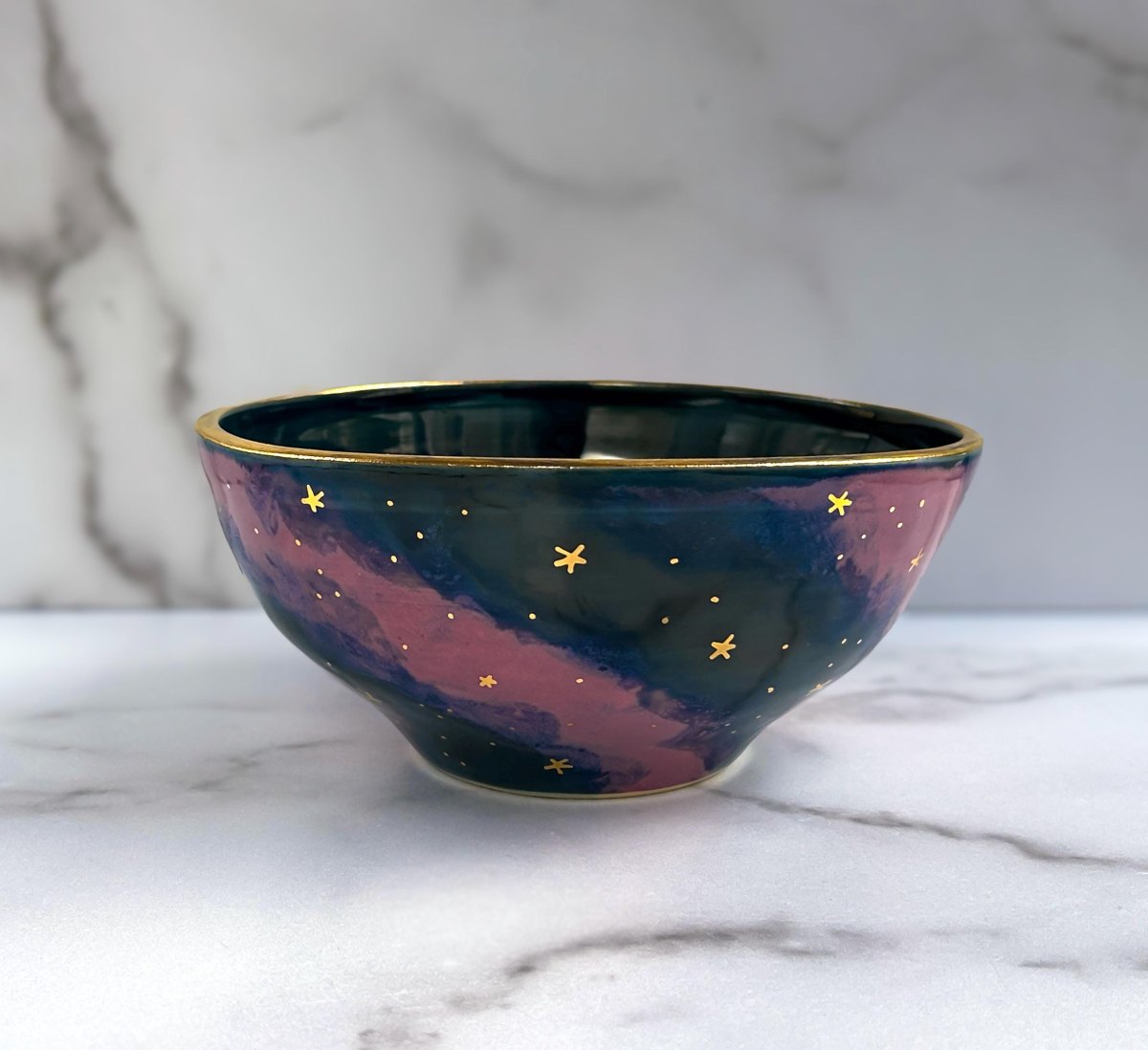 Dunkelblaue Keramikschüssel bemalt mit rosa Galaxie-Nebel und kleinen gelben Sternen